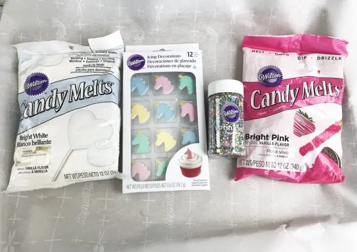 Ingredients for unicorn bark include white and bright pink candy melts, sprinkles and unicorn cupcake toppers.