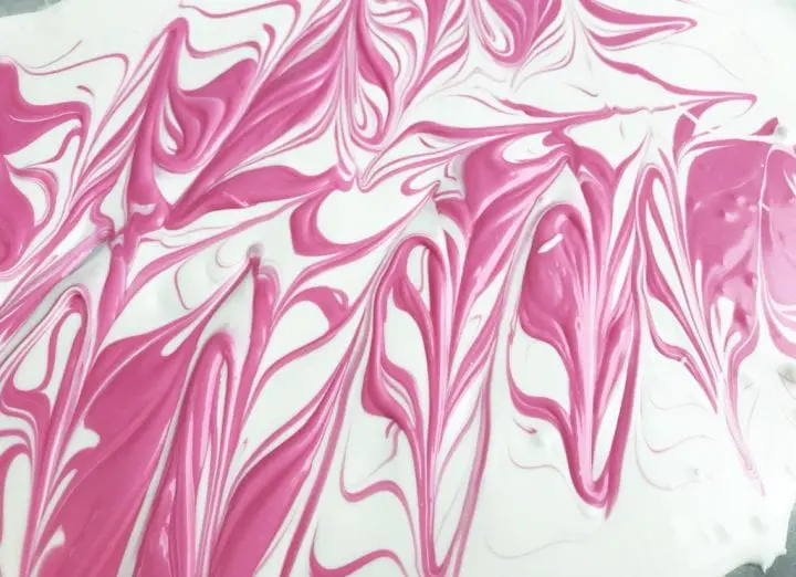 Bright pink melted candy swirled into the white melted candy.