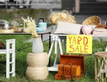 Table with different stuff and sign Yard sale outdoors