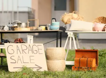 Sign Garage sale written on cardboard near tables with different