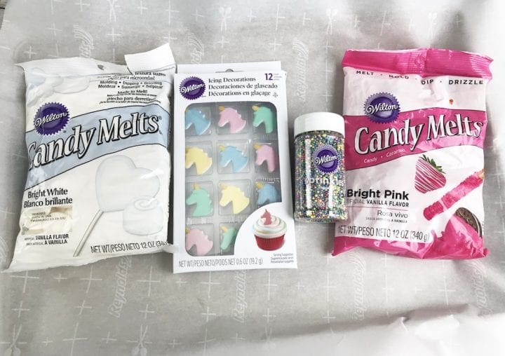 Ingredients for unicorn bark include white and bright pink candy melts, sprinkles and unicorn cupcake toppers.