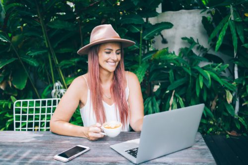 Beautiful blogger in hat working in garden