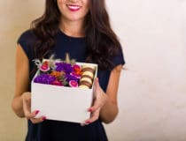 Woman holding a box with flowers and macaroon cookies