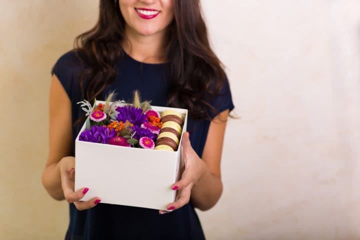 Woman holding a box with flowers and macaroon cookies