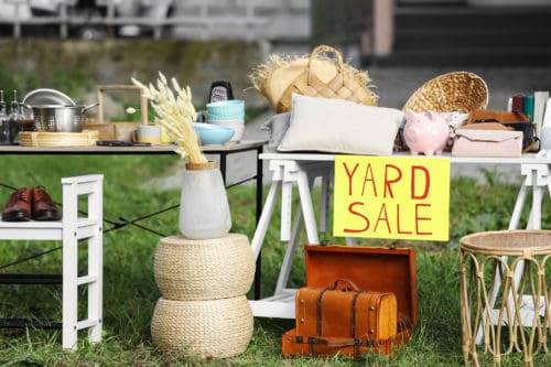 Table with different stuff and sign Yard sale outdoors