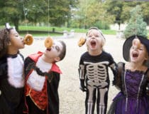 Four young friends on Halloween in costumes eating donuts hangin