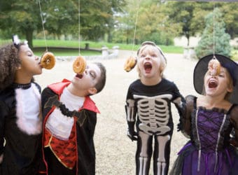 Four young friends on Halloween in costumes eating donuts hangin