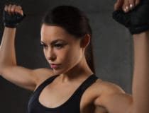 young woman flexing muscles in gym