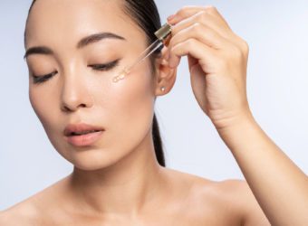 Asian beautiful female is applying eye serum