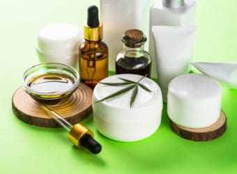 Cannabis cosmetic products on green background close up