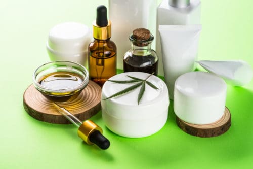 Cannabis cosmetic products on green background close up