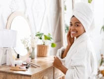 Black Woman Sitting At Toilet Table And Touching Her Perfect Skin
