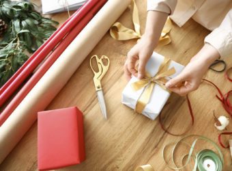 Young woman wrapping Christmas gift at home, closeup