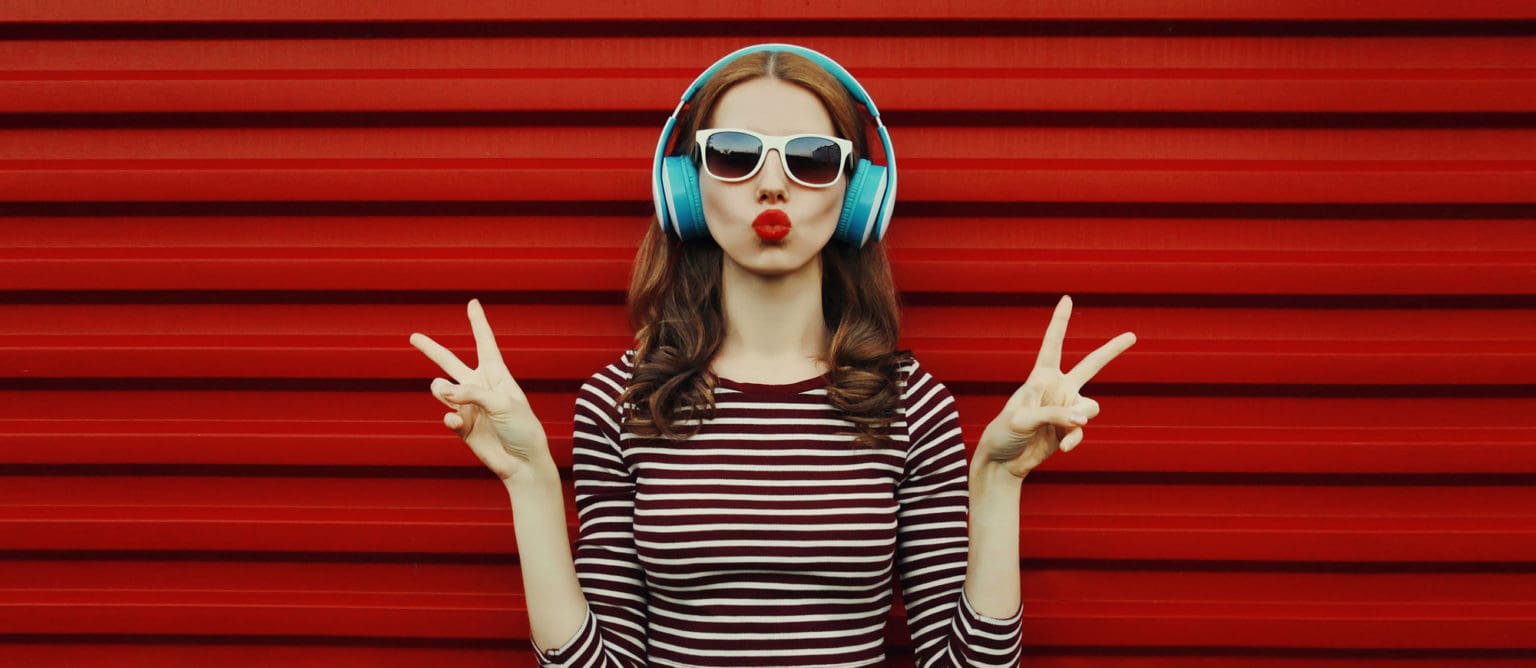 Portrait of young woman in wireless headphones listening to musi