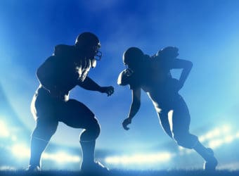 American football players in game, quarterback running Stadium lights