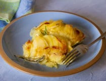 Potato gratin on blue plate Scalloped potatoes or potato bake