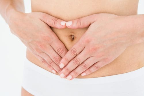 Fit woman with hands on her stomach on white background