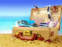 Full open suitcase on tropical beach background, banner