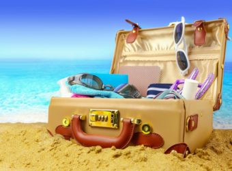 Full open suitcase on tropical beach background, banner