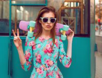 Beautiful and fashion young woman posing with a skateboard on city street