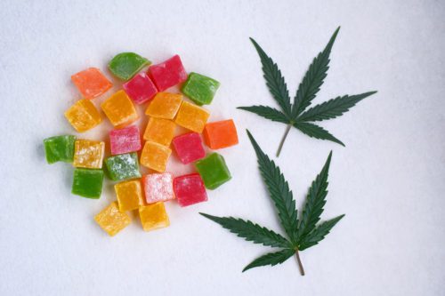 Layout of colorful marmalade and marijuana leaf on white textured background