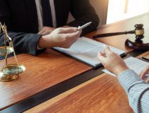 Lawyer working with client discussing contract papers with brass