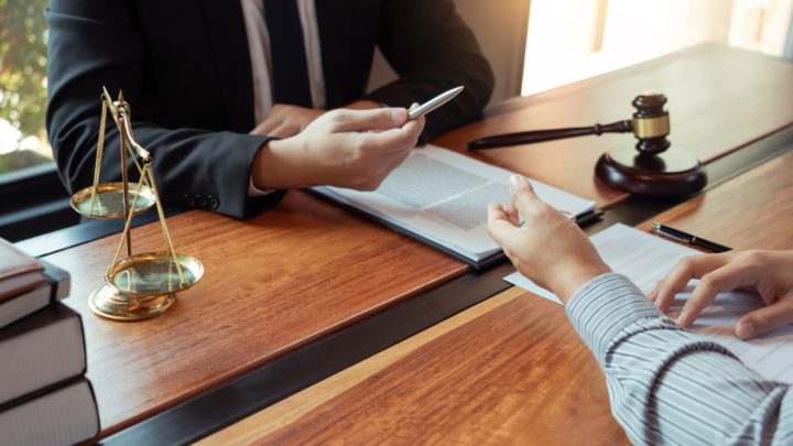 Lawyer working with client discussing contract papers with brass